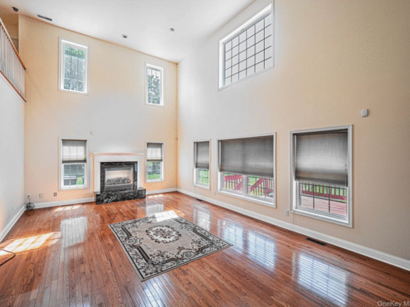 Luxury living room with soaring ceilings, hardwood floors, fireplace, oversized windows, and abundant natural light in Orange County NY home.